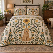 A curly goldendoodle sits beneath a tall folk sunflower, surrounded by mirrored leaves, smaller blooms and birds on warm cream on a quilt set with two matching shams, front view.