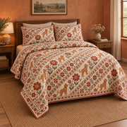 Diagonal bands of small goldendoodles, terracotta folk flowers and leafy motifs create a lively printed stripe on a quilt set with two matching shams, angled view.
