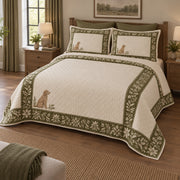A wide olive botanical border surrounds an open cream center, with a small goldendoodle near the lower left on a quilt set with two matching shams, angled view.