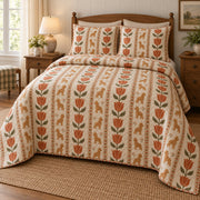 Vertical copper tulip bands alternate with narrow columns of small goldendoodle silhouettes on cream on a quilt set with two matching shams, angled view.