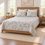 Coral cherry blossom quilt set on a long oak bed, right angle view