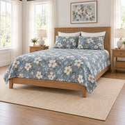 Dusty denim dogwood quilt set on a long oak bed, right angle view