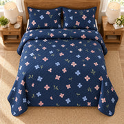 AI mockup, high overhead bedroom view of a hydrangea quilt with pink and blue hydrangea florets scattered on navy and two matching printed pillow covers.