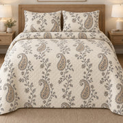 AI mockup, front bedroom view of a paisley quilt with trailing floral vines and neutral paisleys and two matching printed pillow shams.