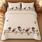 AI mockup, high overhead bedroom view of a mid century modern quilt with five tan and charcoal geometric birds perched along a leafy branch on cream and two matching printed pillow covers.