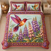 AI mockup, high centered overhead view of colorful hummingbirds hovering over purple lupines with a purple and gold floral border, quilt and two matching printed pillowcases in a neutral bedroom.