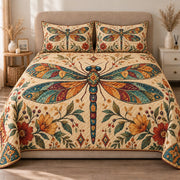 AI mockup, front view of an ornate jewel toned dragonfly with patterned wings amid folk flowers on cream, quilt and two matching printed pillowcases in a neutral bedroom.