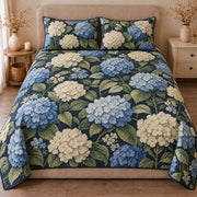 AI mockup, front view of blue and white hydrangea clusters with green leaves on navy, quilt and two matching printed pillowcases in a neutral bedroom.
