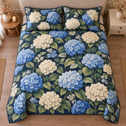 AI mockup, high centered overhead view of blue and white hydrangea clusters with green leaves on navy, quilt and two matching printed pillowcases in a neutral bedroom.